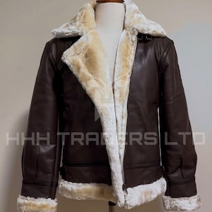Pode incluir: Casaco de couro castanho com forro e acabamento em pele de ovelha creme. O casaco tem fecho de correr e gola larga. O texto "HHH TRADERS LTD" &eacute; vis&iacute;vel.