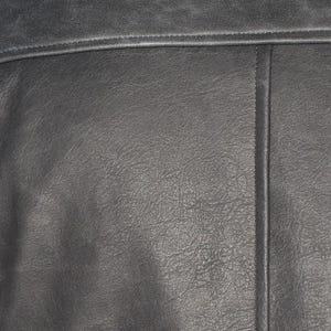 Peut inclure: Gros plan sur une section de cuir gris fonc&eacute;. Le cuir pr&eacute;sente une surface textur&eacute;e avec un grain visible et de subtiles variations de couleur. Une couture horizontale et une couture verticale sont visibles.