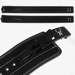 Peut inclure: Ceinture d'halt&eacute;rophilie noire avec des coutures blanches et une boucle noire. La ceinture pr&eacute;sente un logo de t&ecirc;te de cerf avec la lettre "H". La ceinture est faite d'un mat&eacute;riau durable et est con&ccedil;ue pour l'halt&eacute;rophilie.