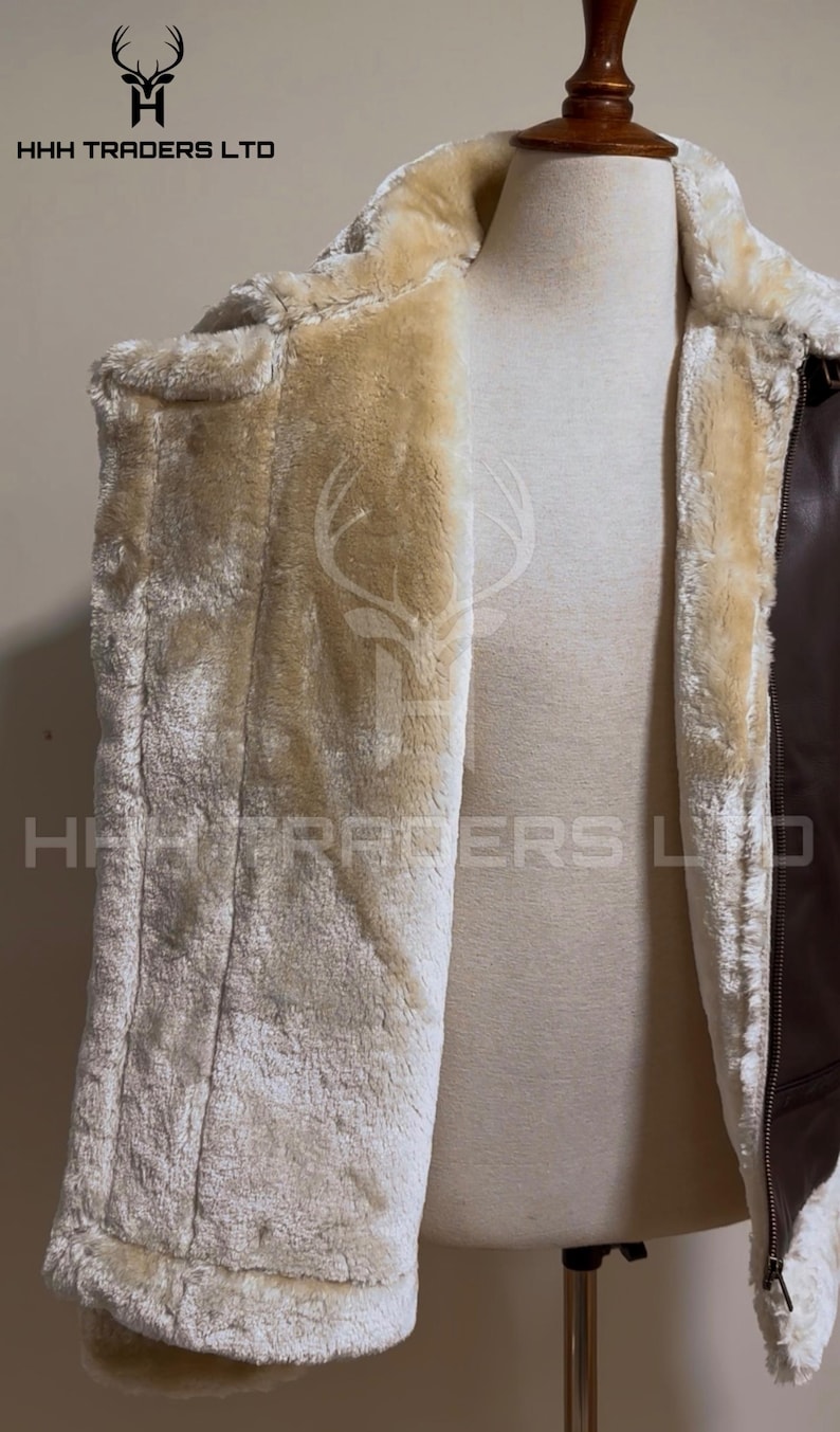 Pode incluir: Casaco de couro castanho com forro de pele sint&eacute;tica creme. O casaco &eacute; exibido em um manequim. O logotipo "HHH TRADERS LTD" &eacute; vis&iacute;vel na parte superior e inferior da imagem.