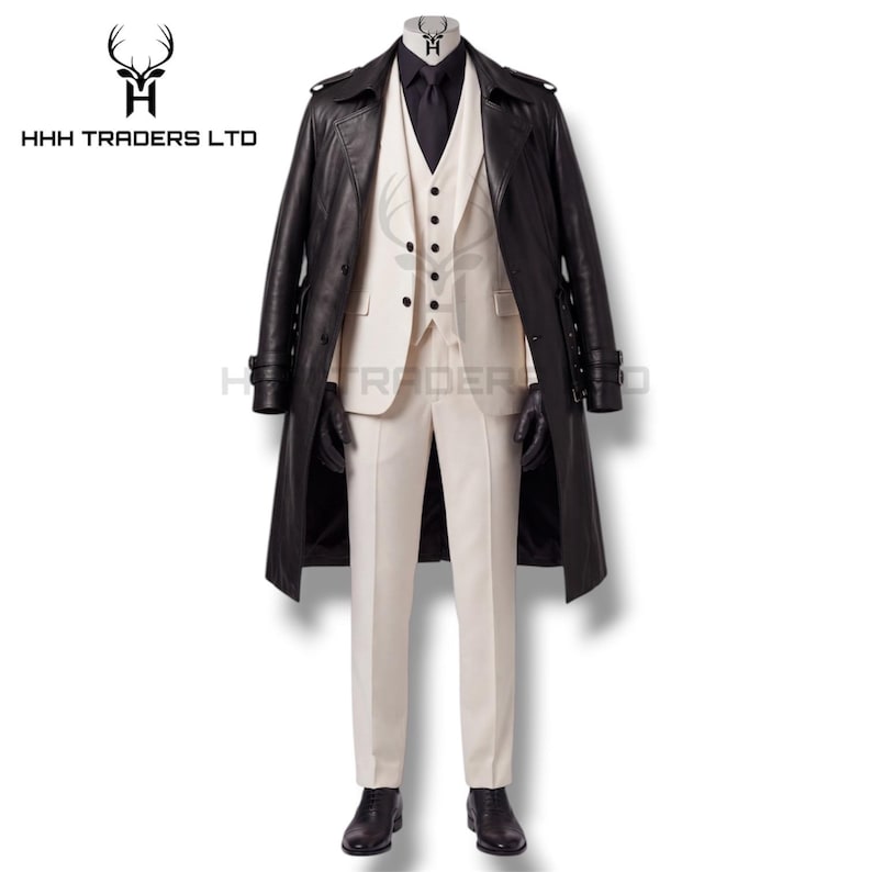 Puede incluir: Un traje formal color crema con camisa y guantes negros, cubierto por una gabardina de cuero negra. El traje incluye chaleco, chaqueta y pantal&oacute;n. Zapatos negros completan el conjunto. El logotipo "HHH TRADERS LTD" es visible en la esquina superior izquierda.