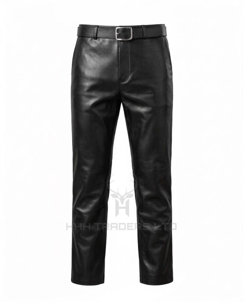 May include: Black leather trousers featuring a smooth finish, a straight-leg cut, and a matching black leather belt with a silver-toned metal buckle. The garment includes a central fly closure and belt loops, with the text HHH TRADERS LTD visible.