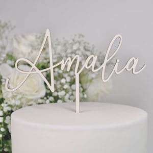 Könnte beinhalten: Weißer Kuchentopper aus Holz mit dem Namen "Amalia" in Kursivschrift.