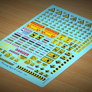 May include: A sheet of yellow and black warning signs and labels for model building. The sheet includes various signs such as "Danger", "Warning", "Radioactive", and "Caution".