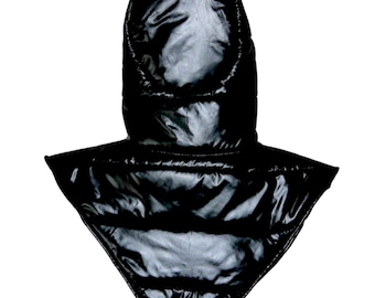 Könnte beinhalten: Eine schwarze, gesteppte Kapuze mit glänzender, glatter Oberfläche. Das Kleidungsstück verfügt über eine spitz zulaufende, dreieckige Basis, die über Schultern und Brustbereich reicht und durchgehend mit horizontalen Steppnähten versehen ist.