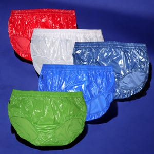 Könnte beinhalten: Fünf Paar glänzende, wasserdichte Unterwäsche in verschiedenen Farben: Rot, Weiß, Blau, Hellblau und Grün. Die Unterwäsche ist aus einem glatten, glänzenden Material gefertigt.