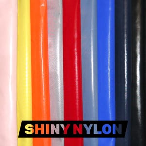 May include: A collection of colorful, shiny nylon fabric samples in various shades, including pink, yellow, orange, red, blue, and black. The text "SHINY NYLON" is displayed in a black and gold banner at the bottom of the image.