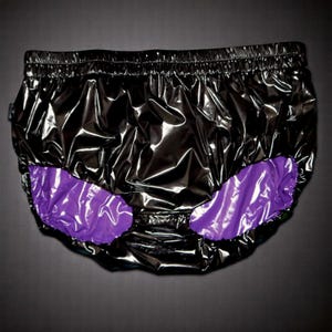 Puede incluir: Ropa interior de nylon negro brillante con forro morado. La ropa interior tiene una cintura elástica.