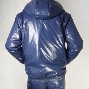 May include: A shiny, navy blue hooded jacket with matching pants. The jacket has a glossy, reflective surface and a fitted waist. The hood is attached and the outfit appears to be made of a synthetic material.