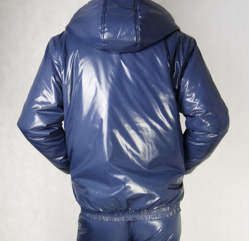 May include: A shiny, navy blue hooded jacket with matching pants. The jacket has a glossy, reflective surface and a fitted waist. The hood is attached and the outfit appears to be made of a synthetic material.
