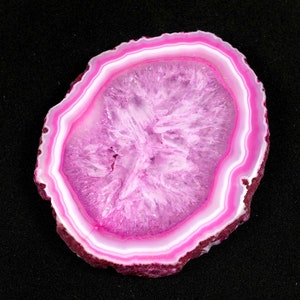 May include: A pink agate slice with white and pink banding. The agate is polished and has a smooth surface.
