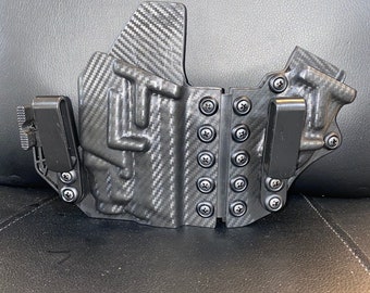 Glock 19, 23, 32, 45 en 19x met Olight Baldr S bijlage Holster in zijspanstijl, afgebeeld in volledig tactisch zwart koolstofvezel Kydex