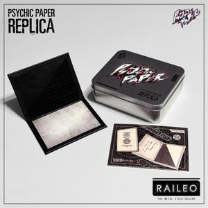 Puede incluir: Una cartera de cuero negro con una inserción de papel blanco está abierta junto a una caja de metal plateado y una tarjeta pequeña. La caja y la tarjeta presentan el texto "PSYCHIC PAPER REPLICA" en una fuente estilizada. La tarjeta también tiene el texto "WHID REPLICA".