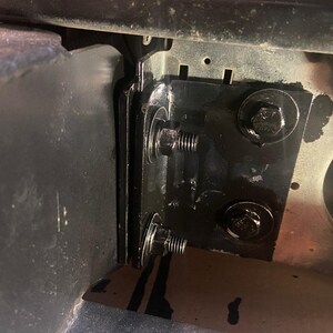 K&ouml;nnte beinhalten: Nahaufnahme einer schwarzen Metallhalterung mit zwei Schrauben und Unterlegscheiben. Die Halterung ist an einer gr&ouml;&szlig;eren Metalloberfl&auml;che befestigt.