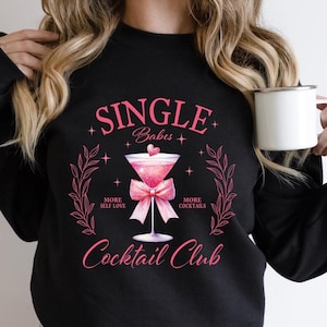 May include: Black sweatshirt with a pink graphic design that says "Single Babes" with a martini glass and a pink bow. The text below the graphic says "More Self Love" and "More Cocktails" and "Cocktail Club".