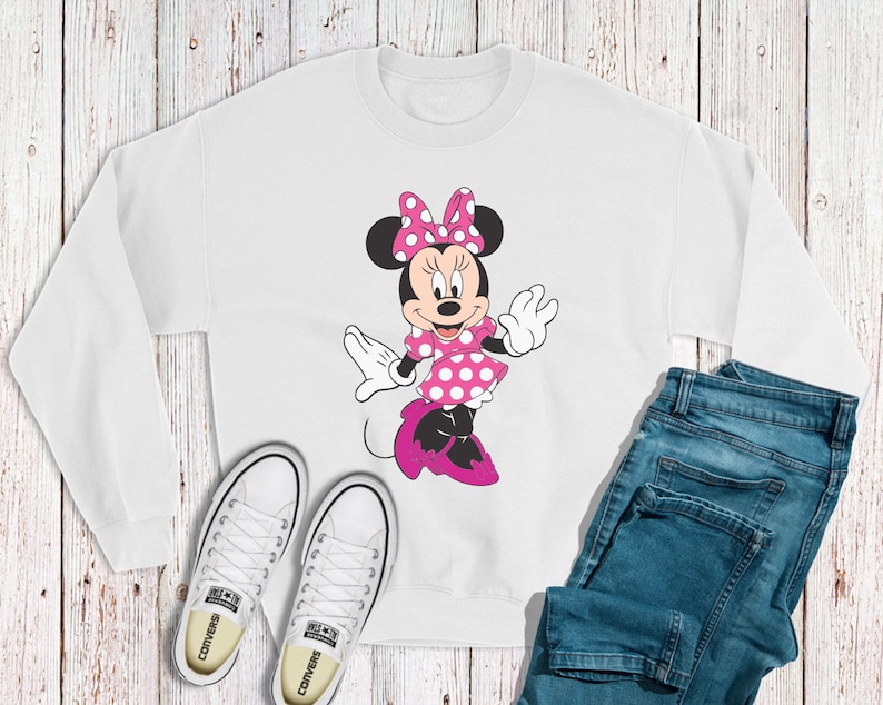 May include: White sweatshirt featuring a pink and white Minnie Mouse design. The sweatshirt has a crew neck and long sleeves.