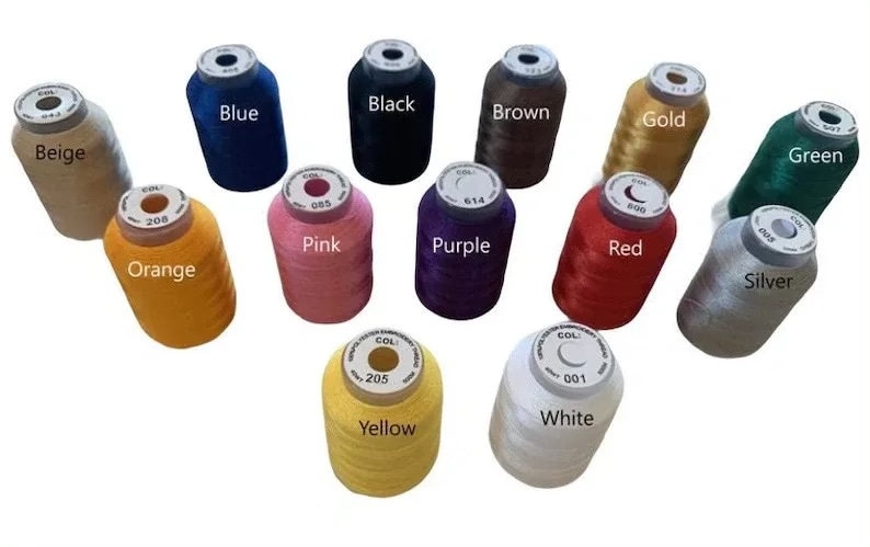 K&ouml;nnte beinhalten: Sortiment von 12 Garnrollen in verschiedenen Farben, darunter Beige, Schwarz, Blau, Braun, Gold, Gr&uuml;n, Orange, Rosa, Lila, Rot, Silber, Wei&szlig; und Gelb.