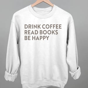以下が含まれることがあります： 「Drink Coffee Read Books Be Happy」という茶色の文字が書かれた白いスウェットシャツです。