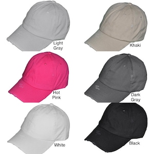 May include: Six distressed baseball caps in different colors: light gray, khaki, hot pink, dark gray, white, and black. Each cap has a slightly distressed look with a frayed edge.