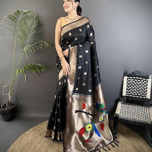 May include: Black silk sari with gold and silver accents. The border features a bird and floral design in shades of blue, yellow, and red. The sari is draped over a person, showcasing its intricate details and elegant drape.