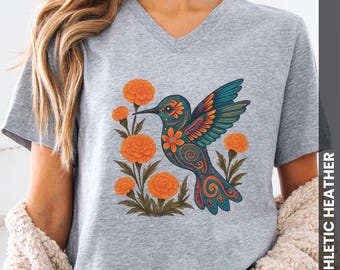 May include: Athletic heather gray V-neck t-shirt featuring a colorful hummingbird design with orange flowers. The hummingbird has teal, orange, and blue details. The shirt has the text "ATHLETIC HEATHER" on the side.