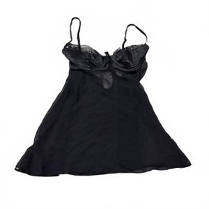 Puede incluir: Un camisón tipo babydoll de color negro con falda fluida y semitransparente, y un corpiño estructurado con tirantes finos ajustables. La parte superior presenta un delicado borde de encaje en el escote y un pequeño lazo decorativo central.