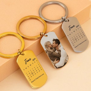 Peut inclure: Trois porte-clés personnalisés avec des étiquettes et des anneaux en métal. Une étiquette dorée affiche "Juin 2024" et un calendrier. Un autre porte-clés présente une photo d'un couple. Le troisième porte-clés est argenté et affiche également "Juin 2024" et un calendrier.