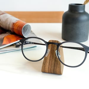 a pair of glasses sitting on top of a wooden stand