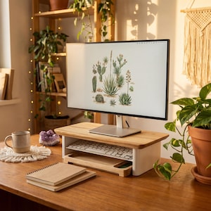A well-organized workspace with a computer monitor, keyboard, and various plants, including a cactus plant, creating a serene and natural atmosphere.