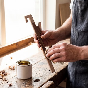 A person is working on a wooden object, likely a tool or piece of furniture, in a workshop setting.