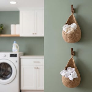 a laundry room with a white washing machine and a basket hanging on the wall. The basket contains folded towels, and there is a bottle of detergent on the counter.