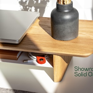 a wooden desk with a laptop, a vase, and some cables, along with a shadow cast on the desk.