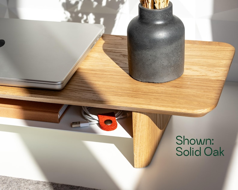 a wooden desk with a laptop, a vase, and some cables, along with a shadow cast on the desk.