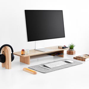 a computer desk with a monitor, keyboard, mouse and headphones