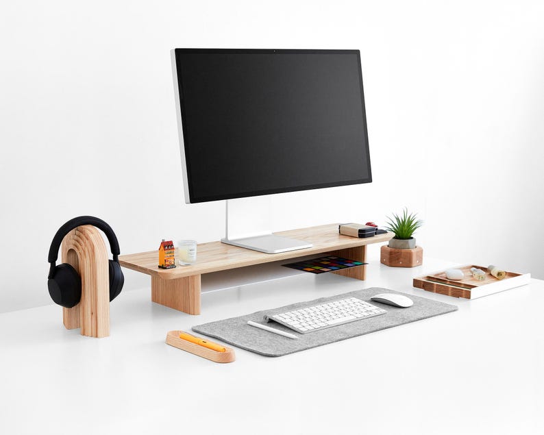 a computer desk with a monitor, keyboard, mouse and headphones