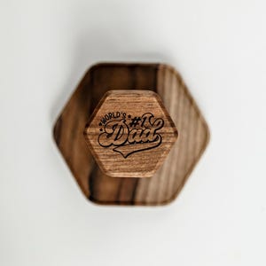 A wooden hexagonal object with the text "World's Dad" engraved on it.
