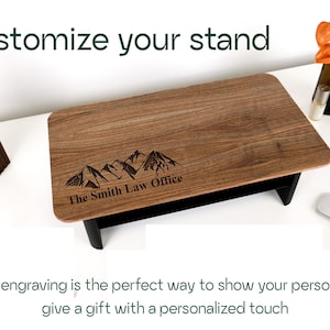 a wooden stand with a mountain design engraved on it, along with a wooden sculpture and a glass bottle. The text overlay encourages custom engraving as a way to showcase one's personality or give a personalized gift.