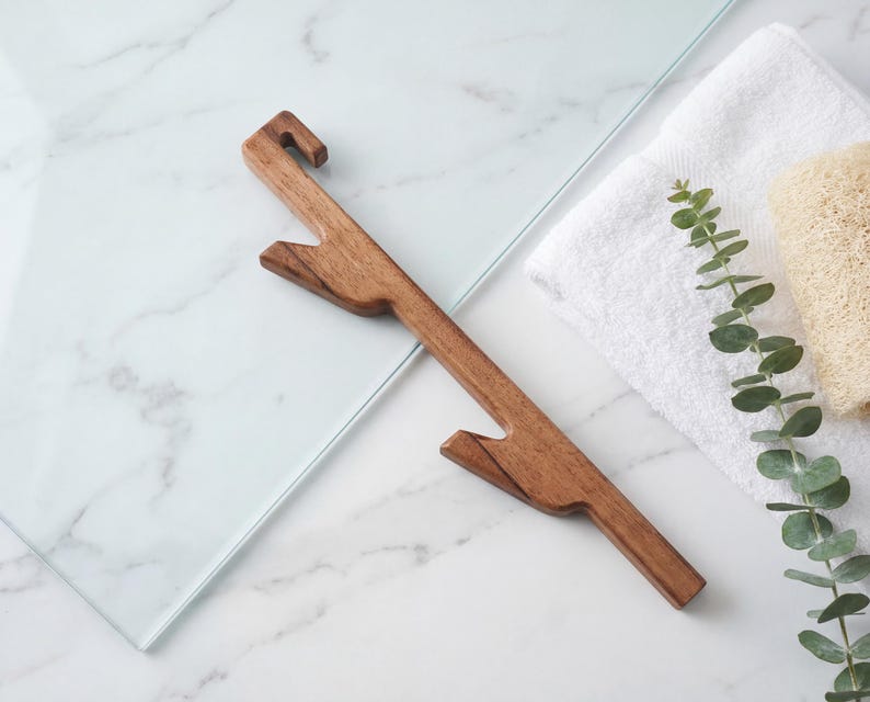 a wooden object, possibly a tool or utensil, placed on a marble surface alongside a white towel and some greenery.