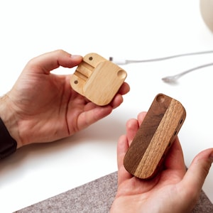 A person's hands holding two wooden objects, one of which appears to be a small wooden box or organizer, while the other is a wooden object with a similar shape.