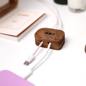 a wooden box with a USB cable plugged into it, placed on a white surface.