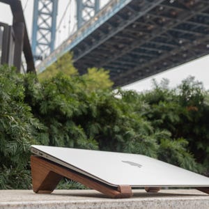 an apple laptop sitting on a ledge under a bridge