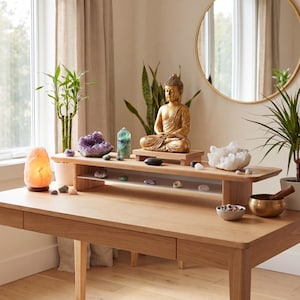 a serene and tranquil indoor setting with a wooden desk adorned with various objects, including a Buddha statue, a crystal bowl, and a potted plant.