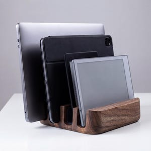 A wooden charging station holds three electronic devices, including a laptop, tablet, and smartphone, neatly organized and ready for use.