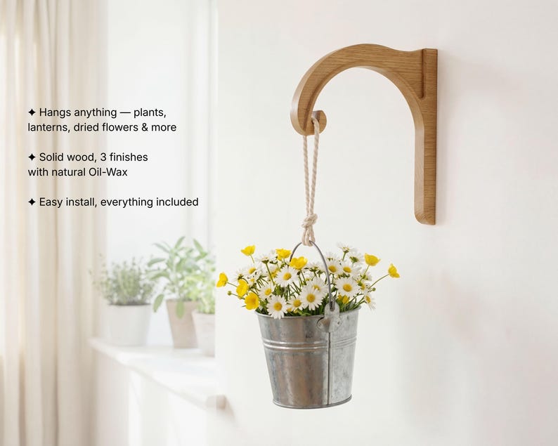 A hanging metal bucket filled with yellow and white flowers is mounted on a wall, with a wooden bracket attached to the wall.
