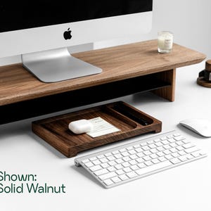 a wooden desk with a computer monitor, keyboard, mouse, and other office supplies arranged on it.