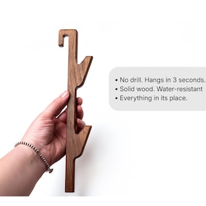 A wooden object, possibly a tool or piece of furniture, is being held in a hand against a white background.
