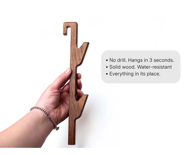 A wooden object, possibly a tool or piece of furniture, is being held in a hand against a white background.