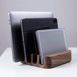 A wooden charging station holds three electronic devices, including a laptop, tablet, and smartphone, neatly organized and ready for use.