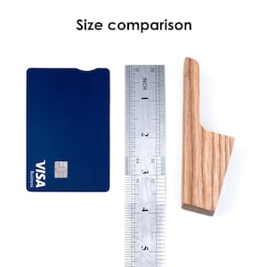 a blue Visa credit card, a ruler, and a wooden object, likely a toothbrush, arranged on a white background.