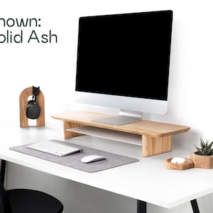 a modern, minimalist workspace with a white desk, a computer monitor, a keyboard, a mouse, and a potted plant.